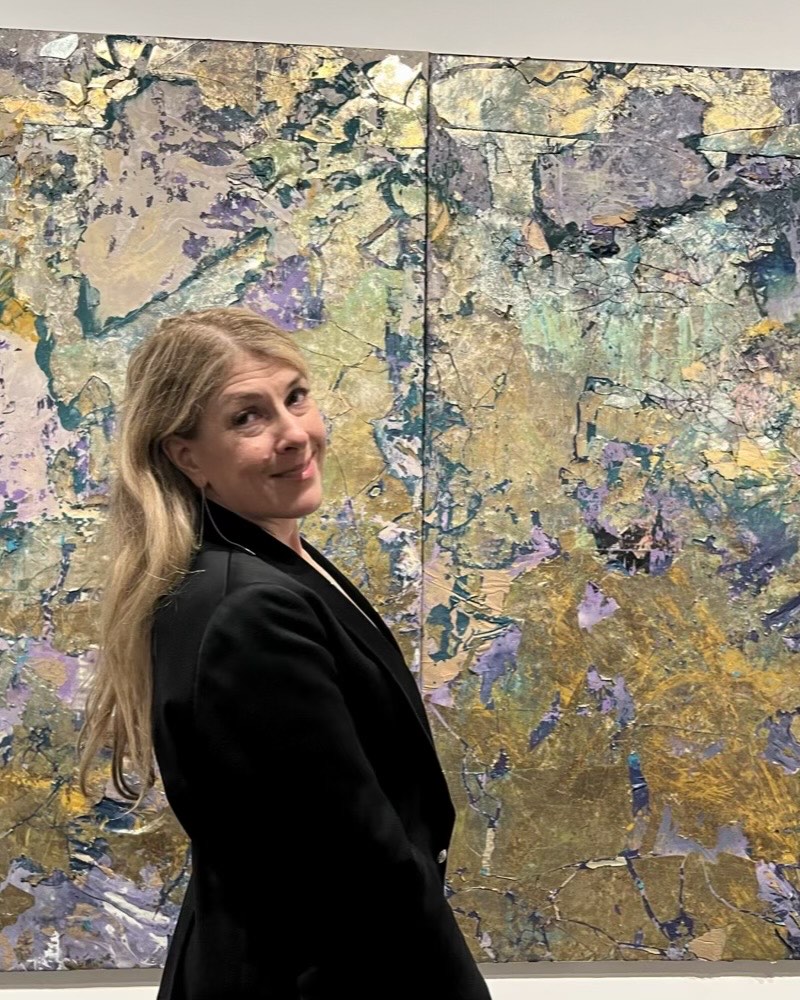 Christina LaManque before a gold and lavender abstract painting